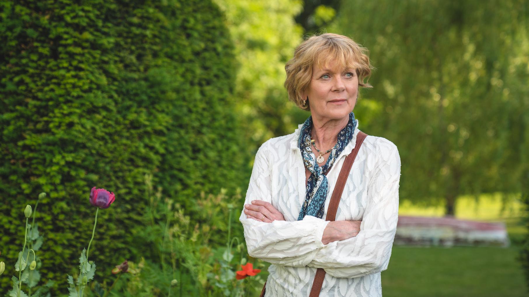 Judith Potts is sure she heard a gunshot from her neighbor Stefan Dunwoody's property. Credit: Masterpiece, Monumental Television, and UKTV Judith Potts stands outside with arms crossed