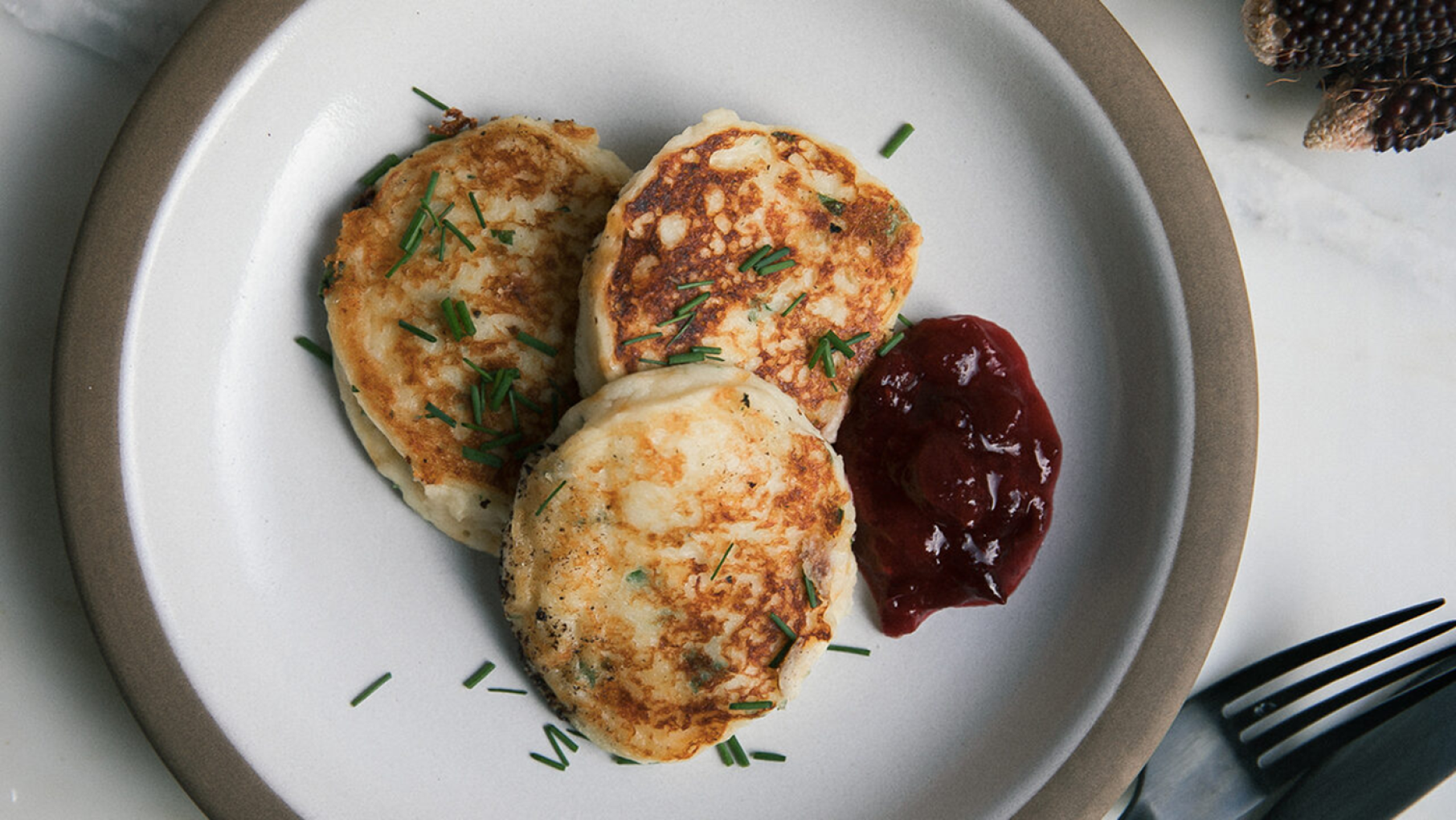 Credit: PBS Three mashed potato pancakes on a plate with cranberry sauce