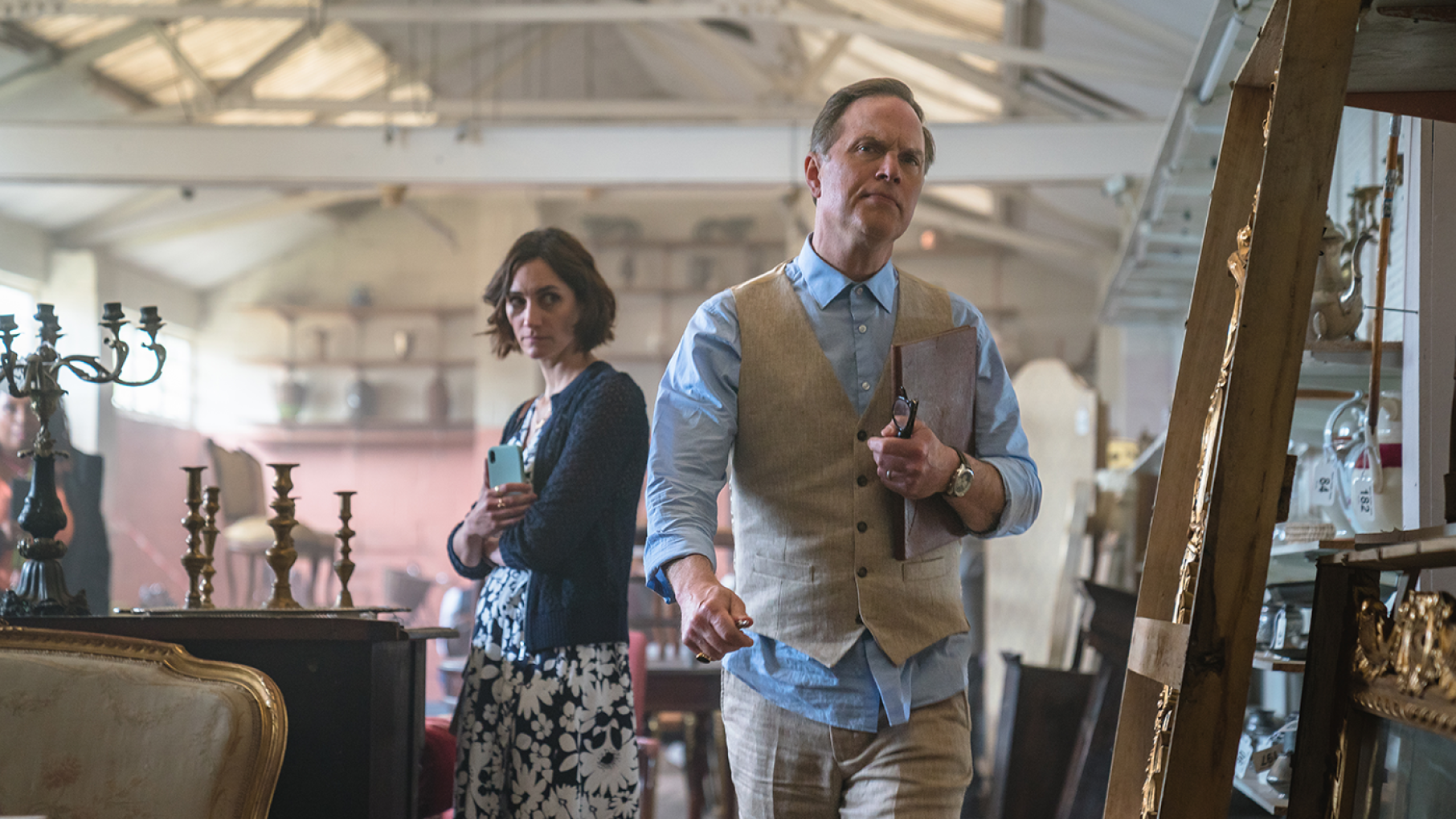 Becks helps Judith and Suzie look into Elliot Howard, whom Judith suspects was involved in the murder of Stefan Dunwoody. Credit: Masterpiece, Monumental Television, and UKTV Becks looks surreptitiously at Elliot Howard as he looks offscreen