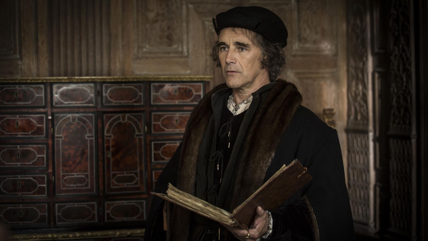 As Cromwell solidifies the king's position as head of the church, he grows in influence. Credit: Masterpiece Thomas Crowmell stands holding a large book