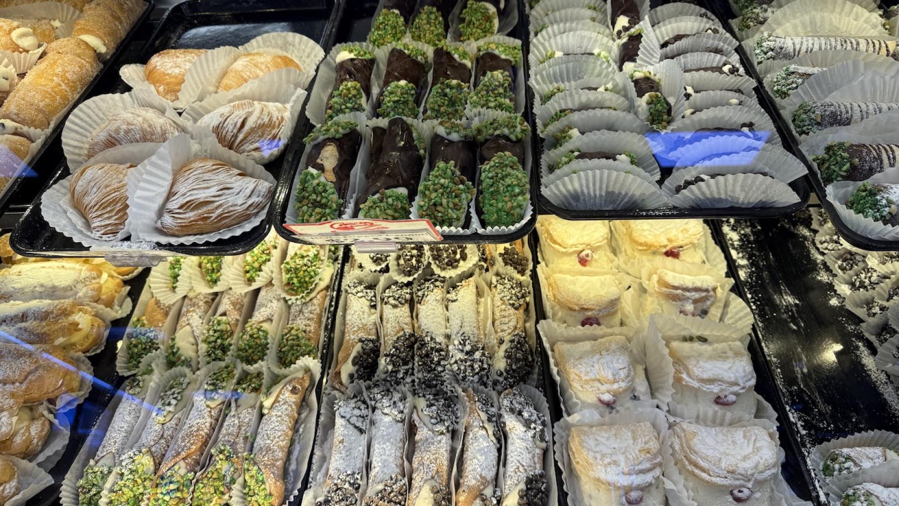 Trays of cannoli and other Italian sweet treats in a display case