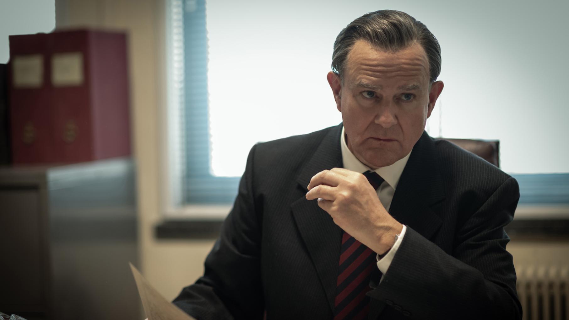 Hugh Bonneville is DCS Brian Boyce in 'The Gold.' Credit: Masterpiece A man sits in a suit at a desk