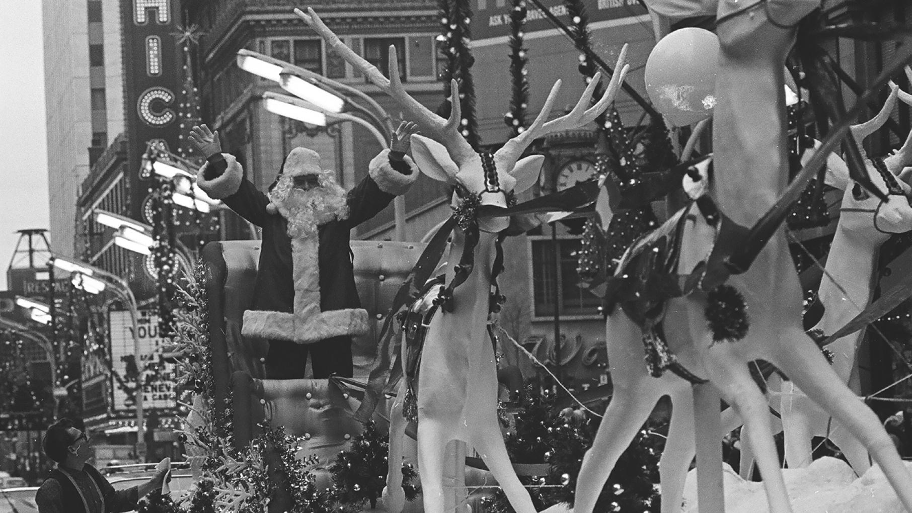 Santa Claus came to town on November 29, 1964. Credit: ST-30004549-0007, Chicago Sun-Times collection, Chicago History Museum A black and white image showing a man dressed as Santa on a float with reindeer statues out in front of him