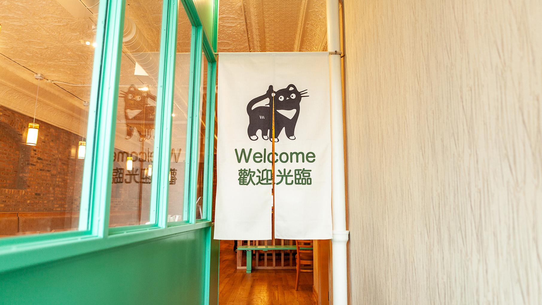 Minyoli is a Taiwanese restaurant in Andersonville that's among the new restaurants participating in Chicago Restaurant Week. Credit: Aliya Ikhumen for WTTW A banner with a cat and "Welcome" in English and Chinese at the entrance to a restaurant