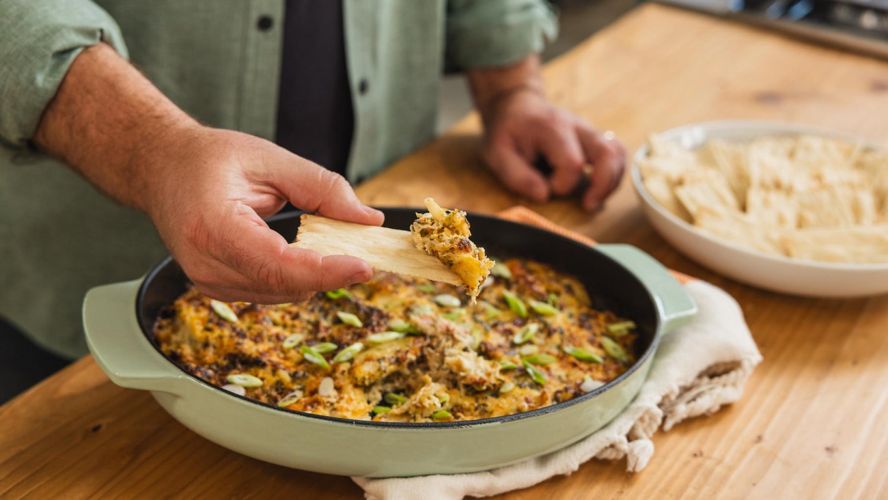 Credit: Homemade Live! A hand dips a cracker into a dish of cheesy dip