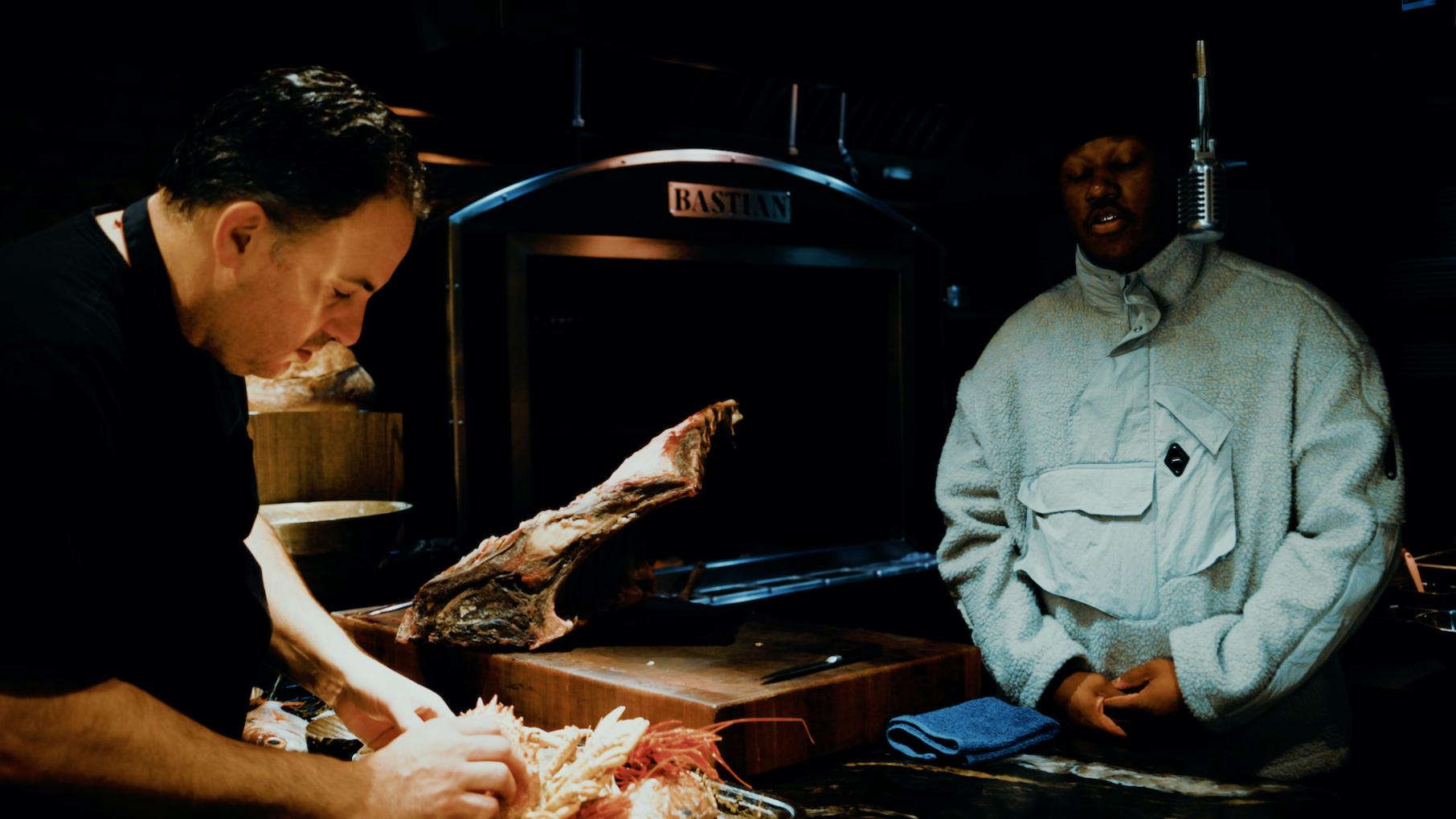 Doug Psaltis preps food in a dark kitchen while Blvck Svm raps 