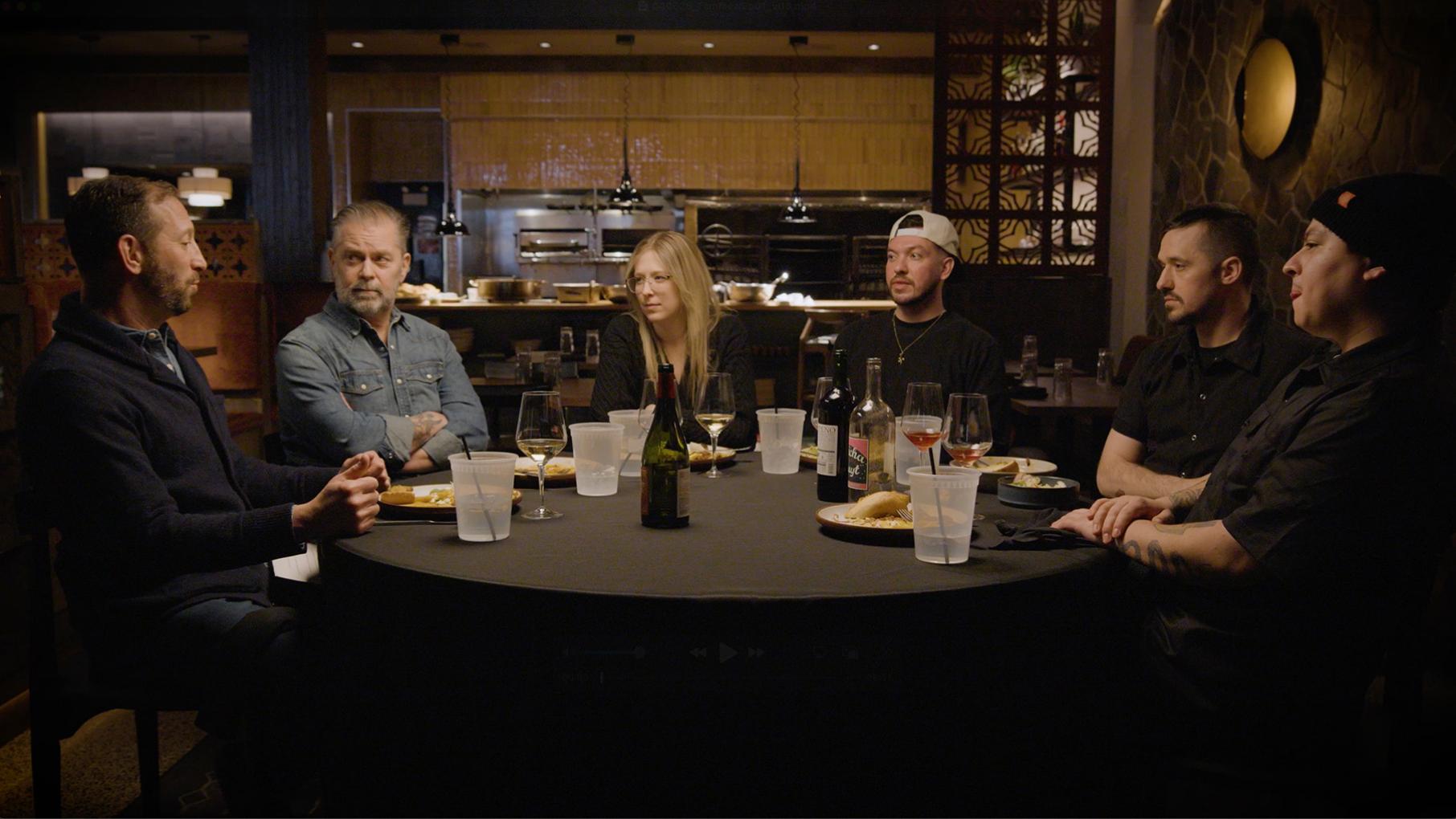 Veteran food journalist Ari Bendersky hosts 'Family Meal,' which visits Brasero in its first episode. Credit: Bottle Rocket Media A group of people sit around a table in a darkened restaurant