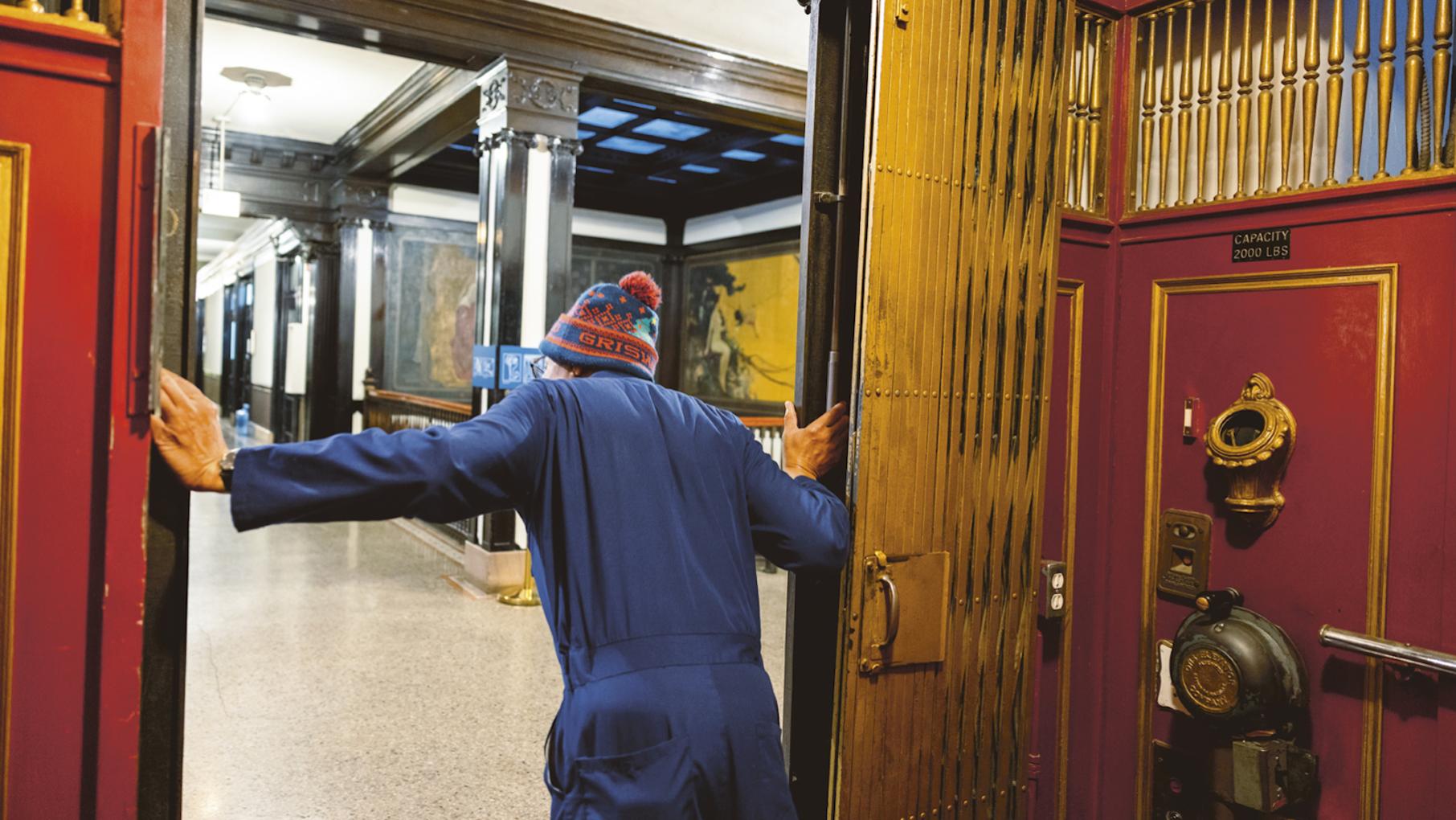 Among the Fine Arts Building's distinctions are the legendary elevators, the last manually operated lifts in the city of Chicago. Credit: Provided A man leans out of an antique elevator, seen from inside the elevator