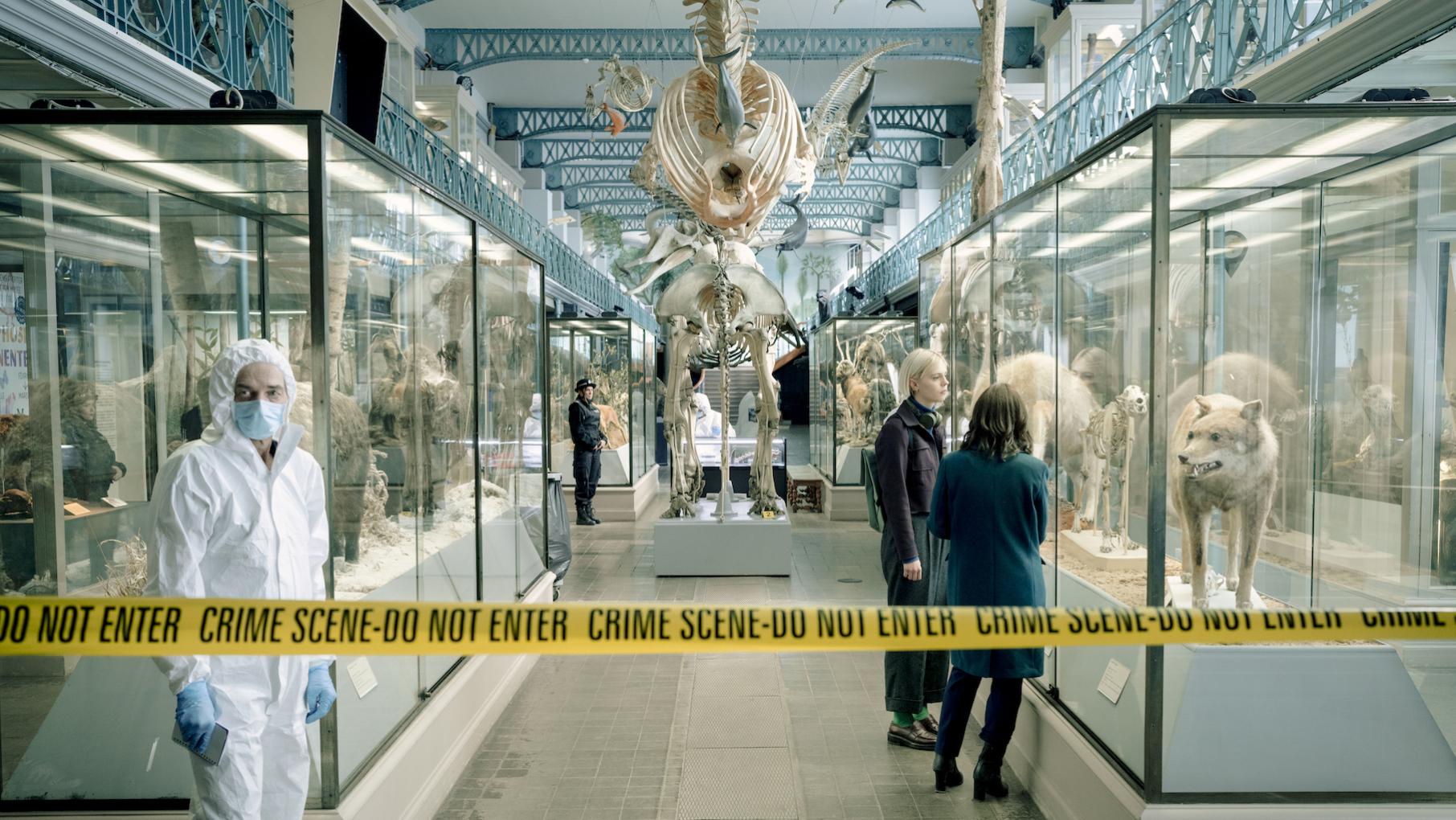 Bea and Patience behind crime scene tape in a natural history museum