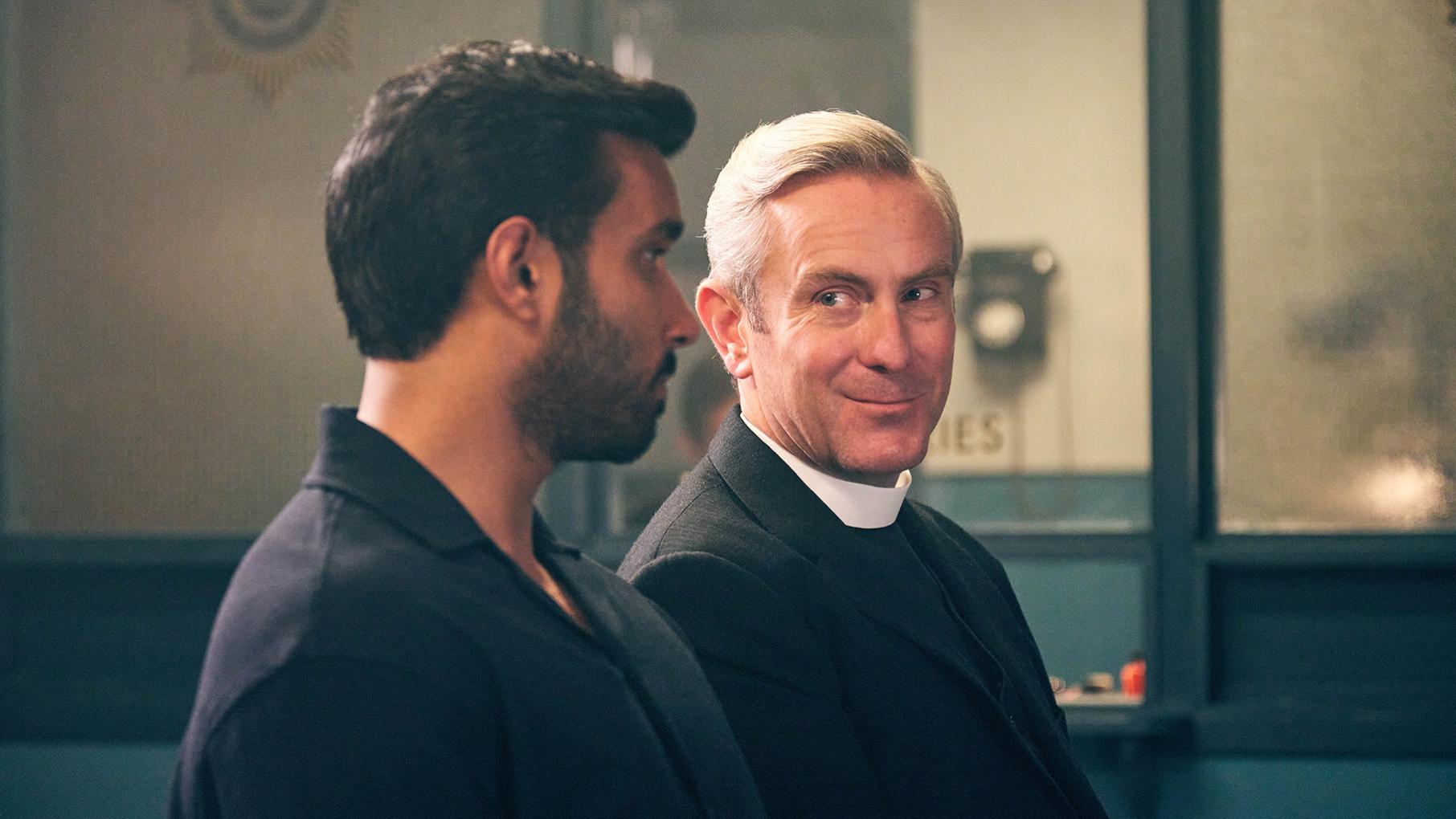Alphy isn't a fan of fellow vicar David, but helps him nonetheless when he ends up embroiled in the investigation of a murder. Credit: Kudos, ITV, and Masterpiece Alphy and Davide Lane sit next to each other