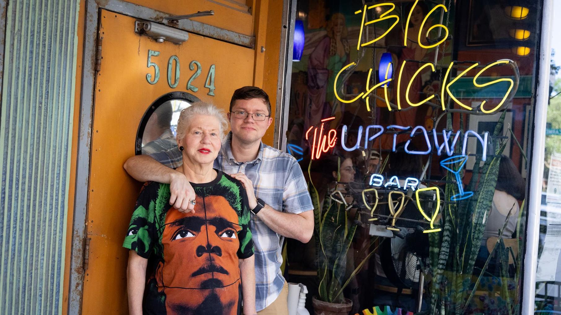 Big Chicks isn’t just a bar – it’s an art gallery, community center, and LGBTQ+ haven. Michelle Fire has run the establishment for decades, more recently with the help of her son, Michael Sanders. Credit: Kathleen Hinkel for WTTW Michelle Fire and Michael Sanders stand together in front of Big Chick's, smiling and posing for the photo.