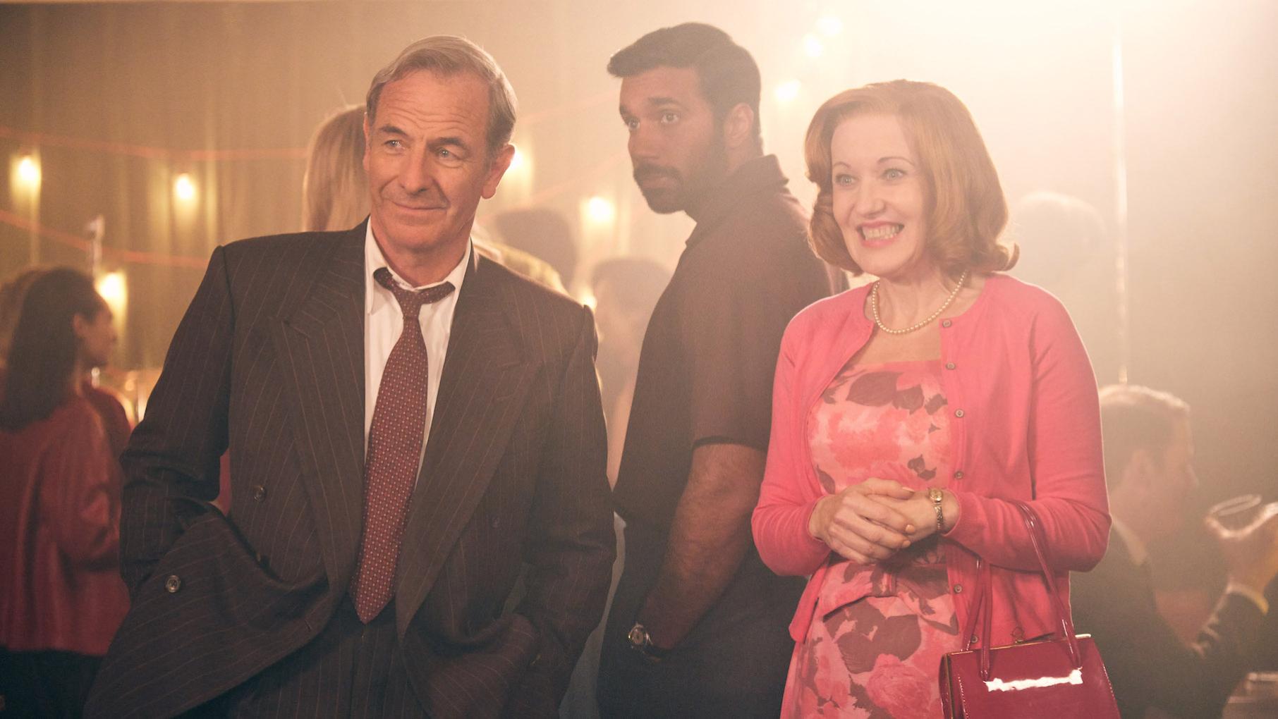 Geordie forces Alphy out for his birthday, and invites Meg. Credit: Kudos, ITV, and Masterpiece Geordie and Cathy smile at something while Alphy stands behind them