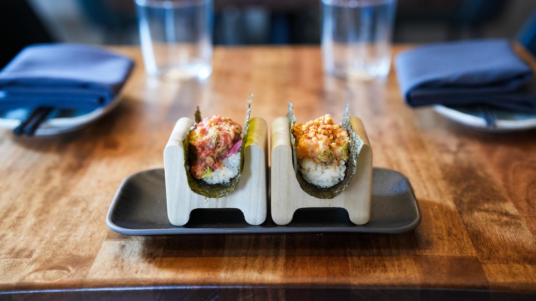 Two hand rolls on a table in wooden holders