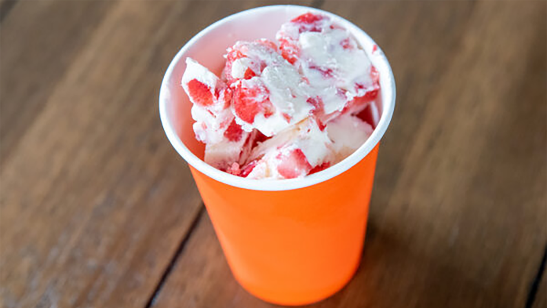 Credit: PBS KIDS An orange cup on a wooden table filled with frozen yogurt with strawberries