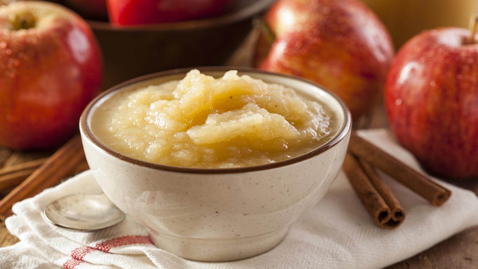 Applesauce in a bowl in front of apples