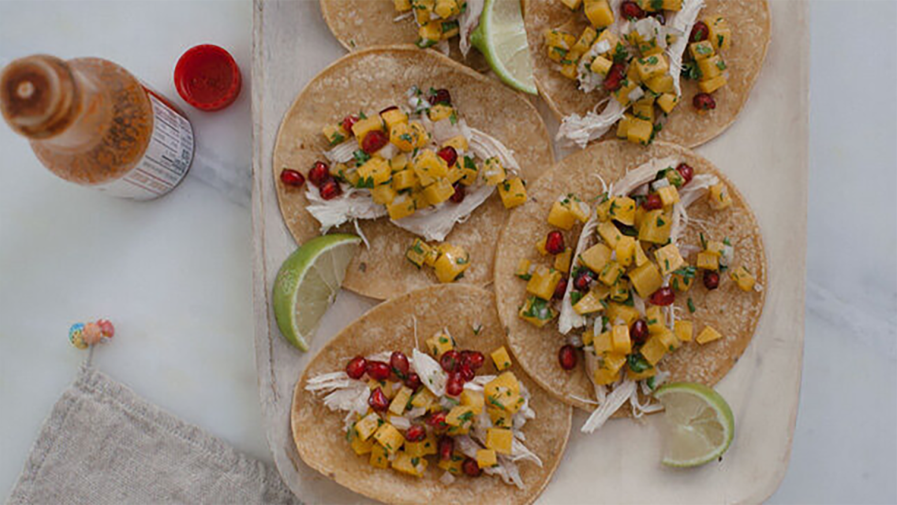 Tacos seen from above with lime slices and hot sauce