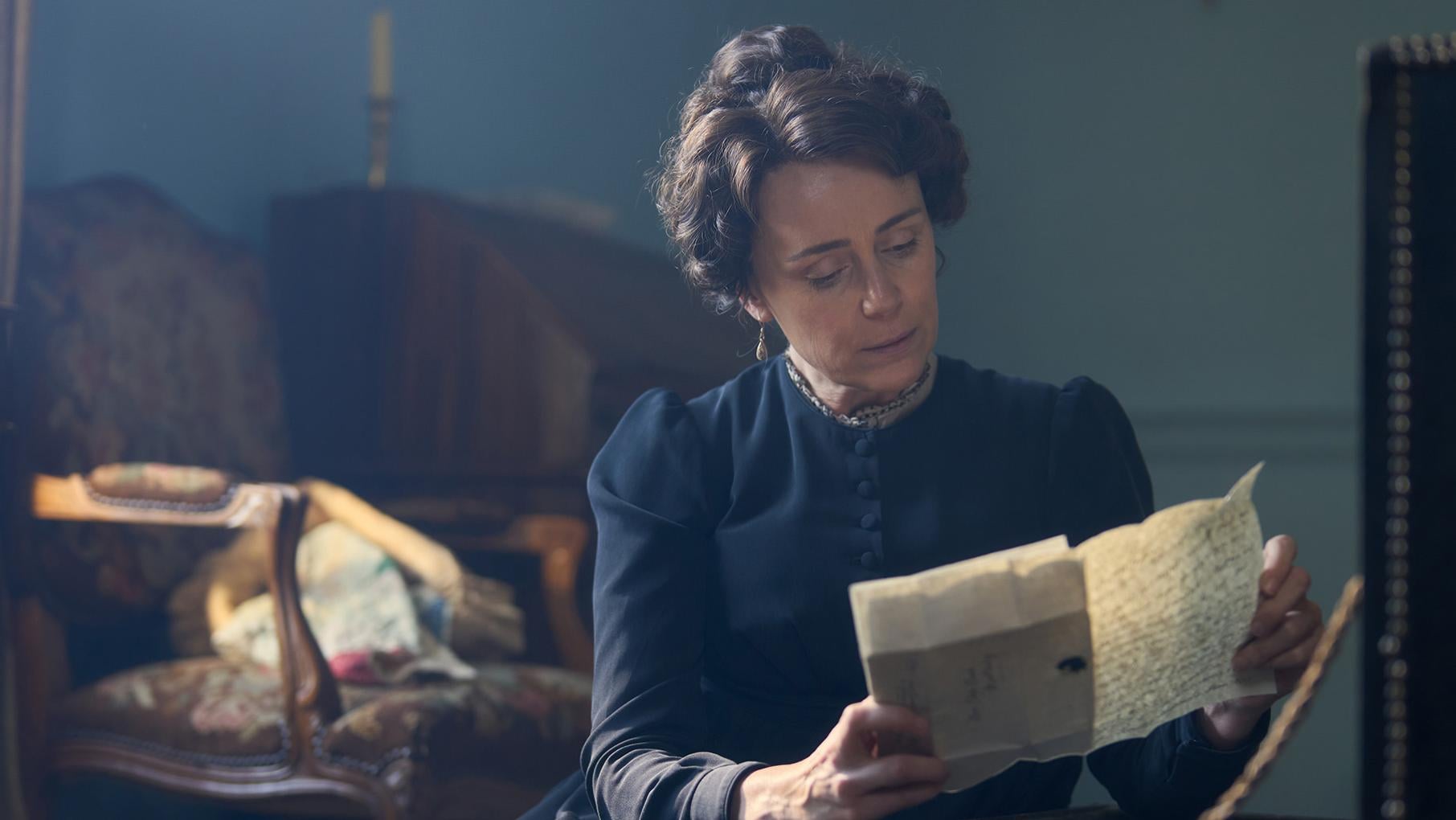 Cassandra Austen sits in black reading a letter