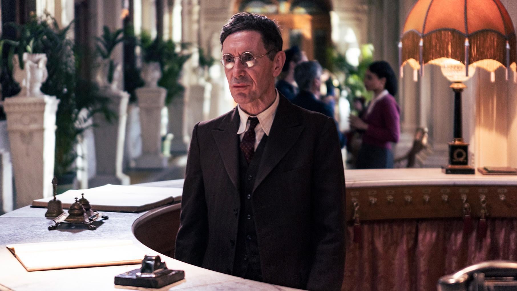 Mr Kind stands behind the curved desk of a hotel