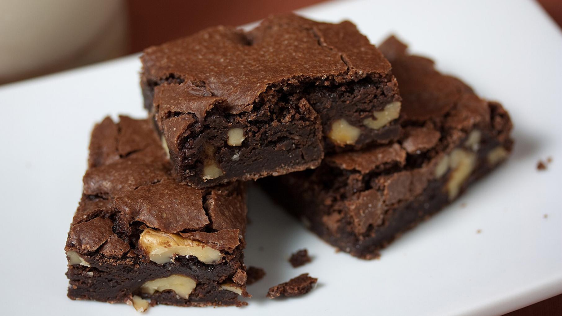 Three brownies with nuts on them on a plate