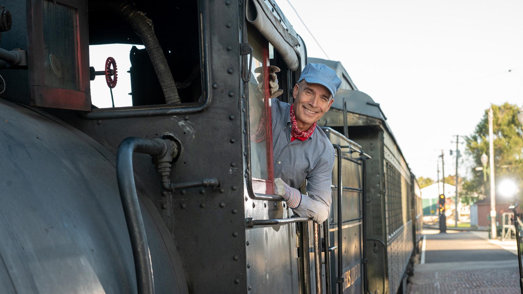 Geoffrey Baer sticks his head out the side of a train