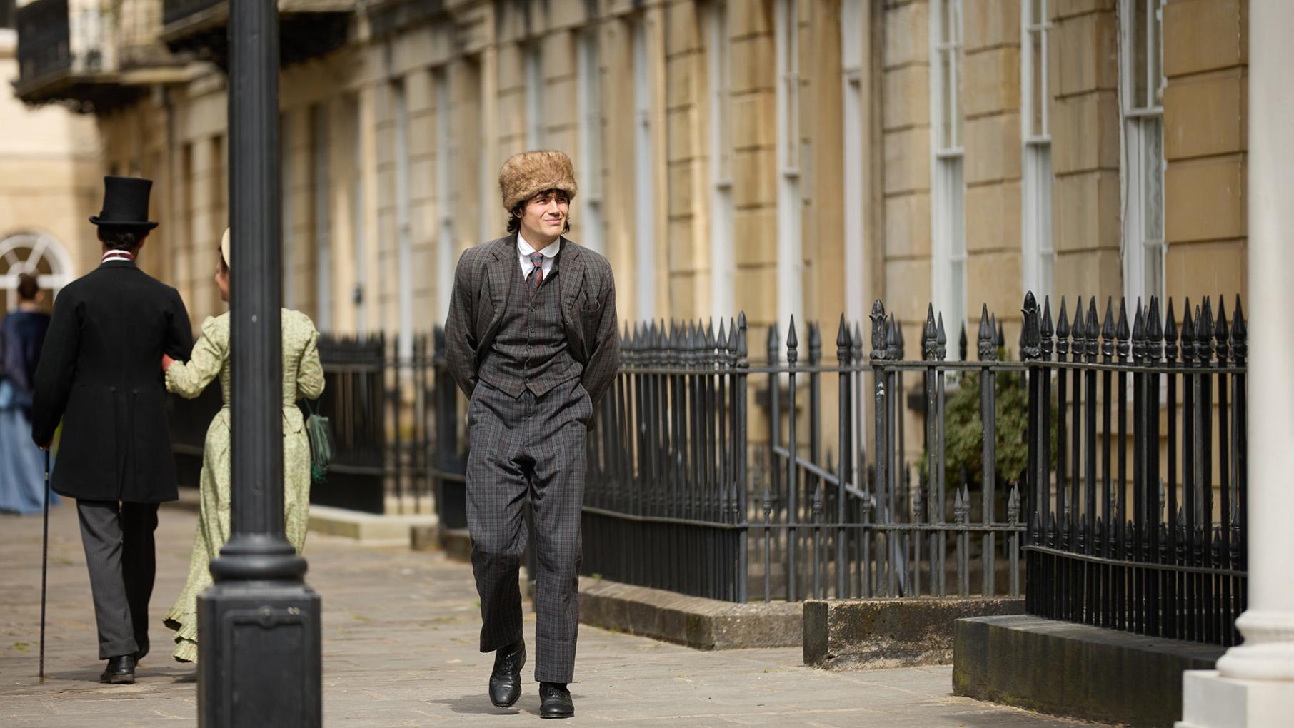 Bosinney walks down the street with a fur cap on