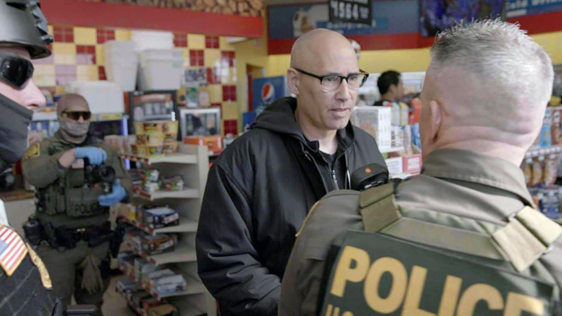 Frontline correspondent A.C. Thompson, center, speaks with former commander-at-large of the Border Patrol, Greg Bovino, who is turned away from the camera