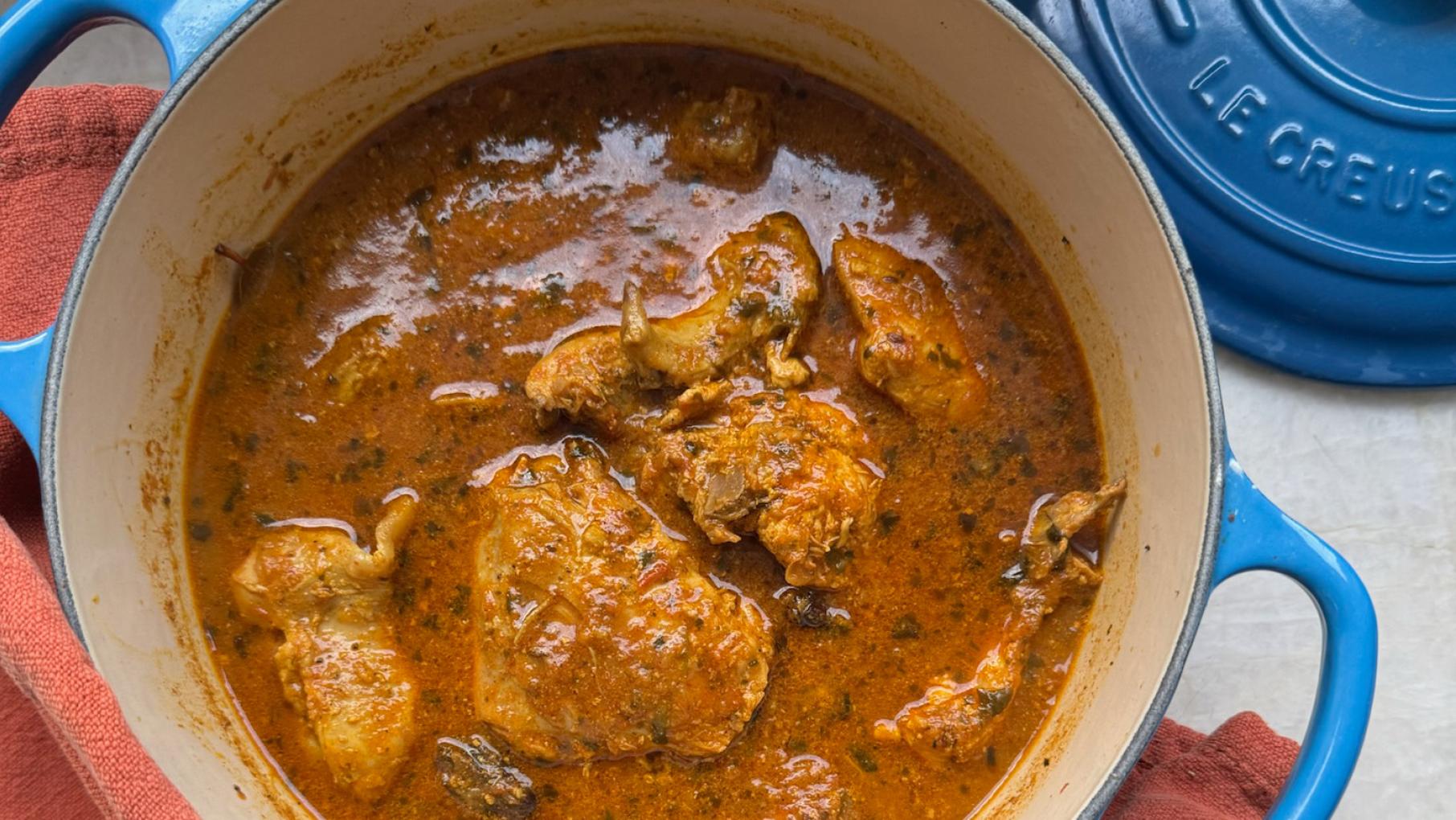 A blue Le Creuset pot with chicken curry in it