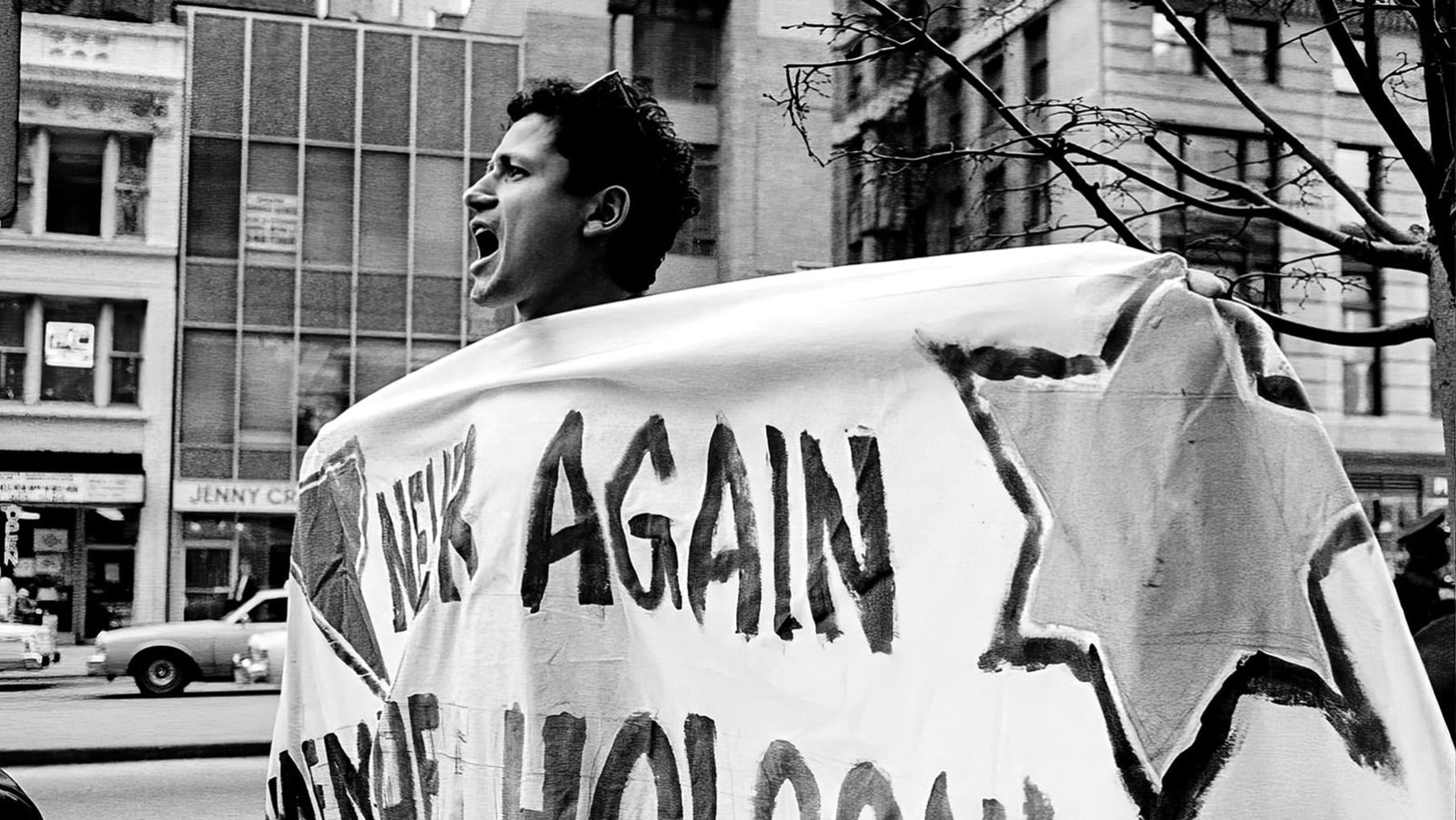 Danny Sotomayor marching with a large banner reading, "Never Again."