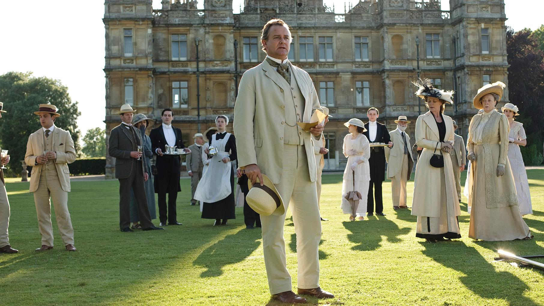 A garden party at Downton Abbey with Robert, the staff, and more standing on the lawn