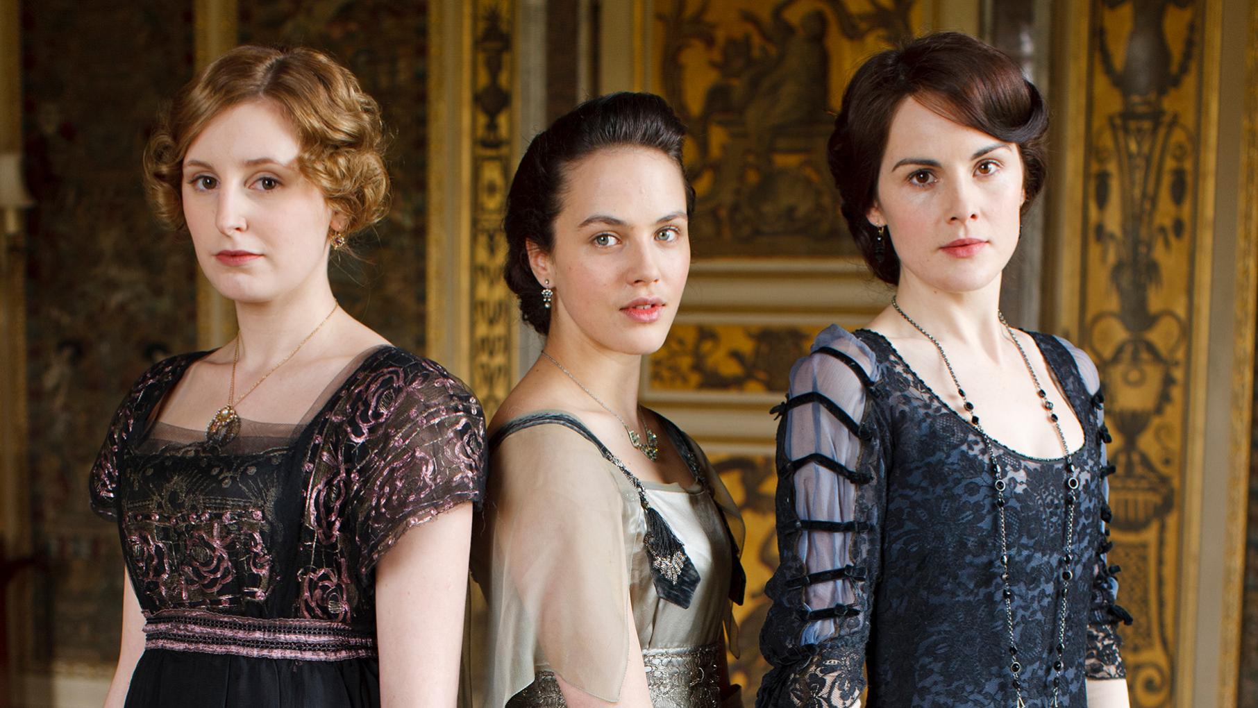 The three Crawley sisters stand next to each other in an ornate room