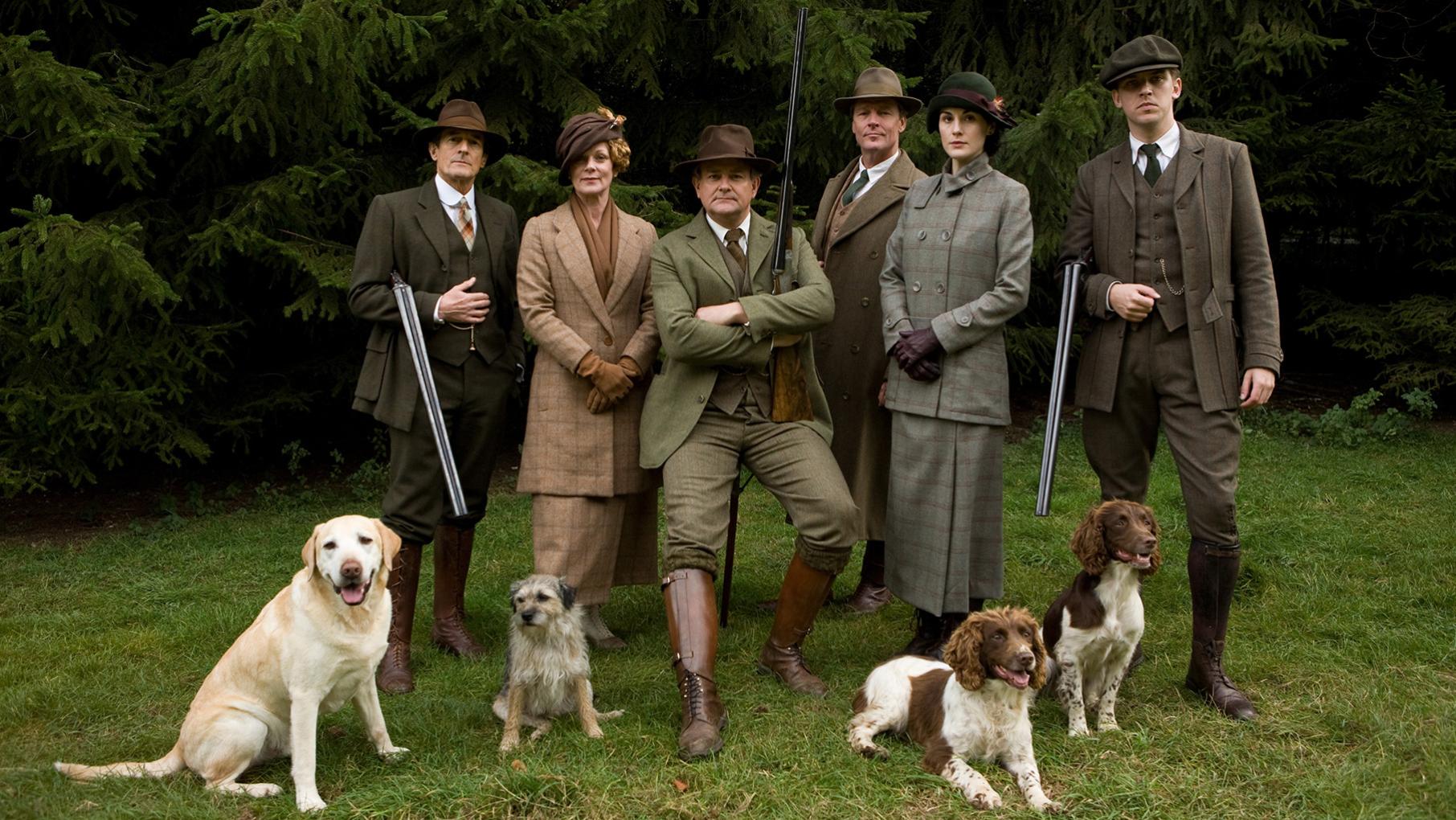 The Crawleys and other pose in hunting garb and guns outside with dogs