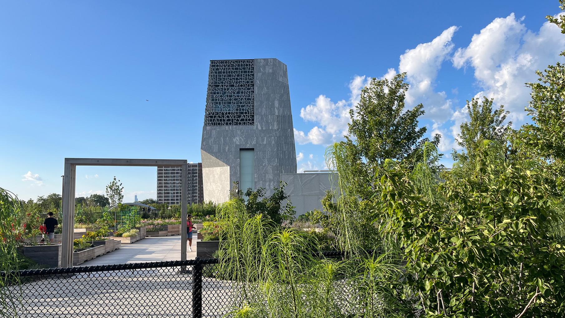 The Obama Center seen over a fence and through its rooftop garden against a blue sky