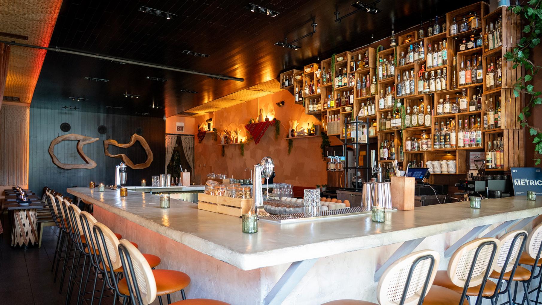 A bar with a large selection of bottles in cubbies on the wall