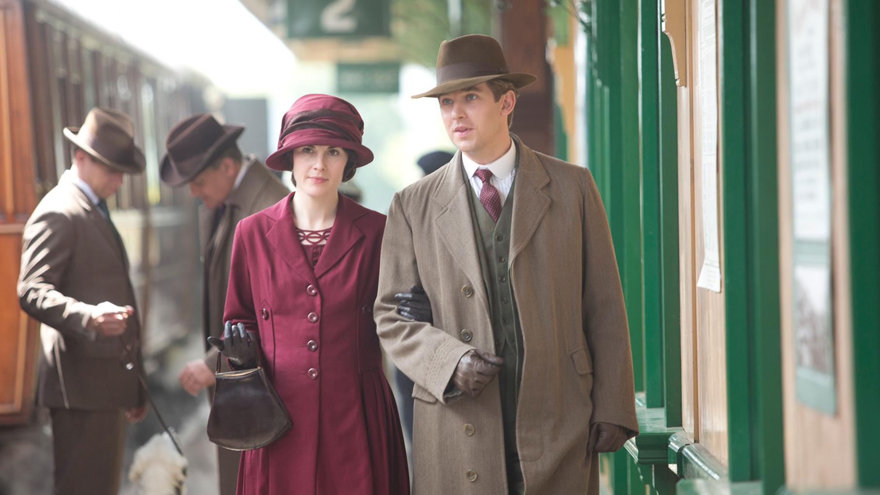 Matthew and Mary stand next to each other at a train station