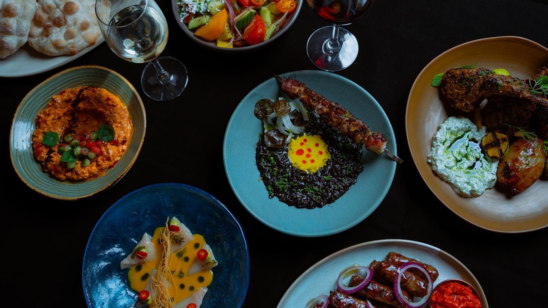 Plates of food and glasses of wine seen from above on a table