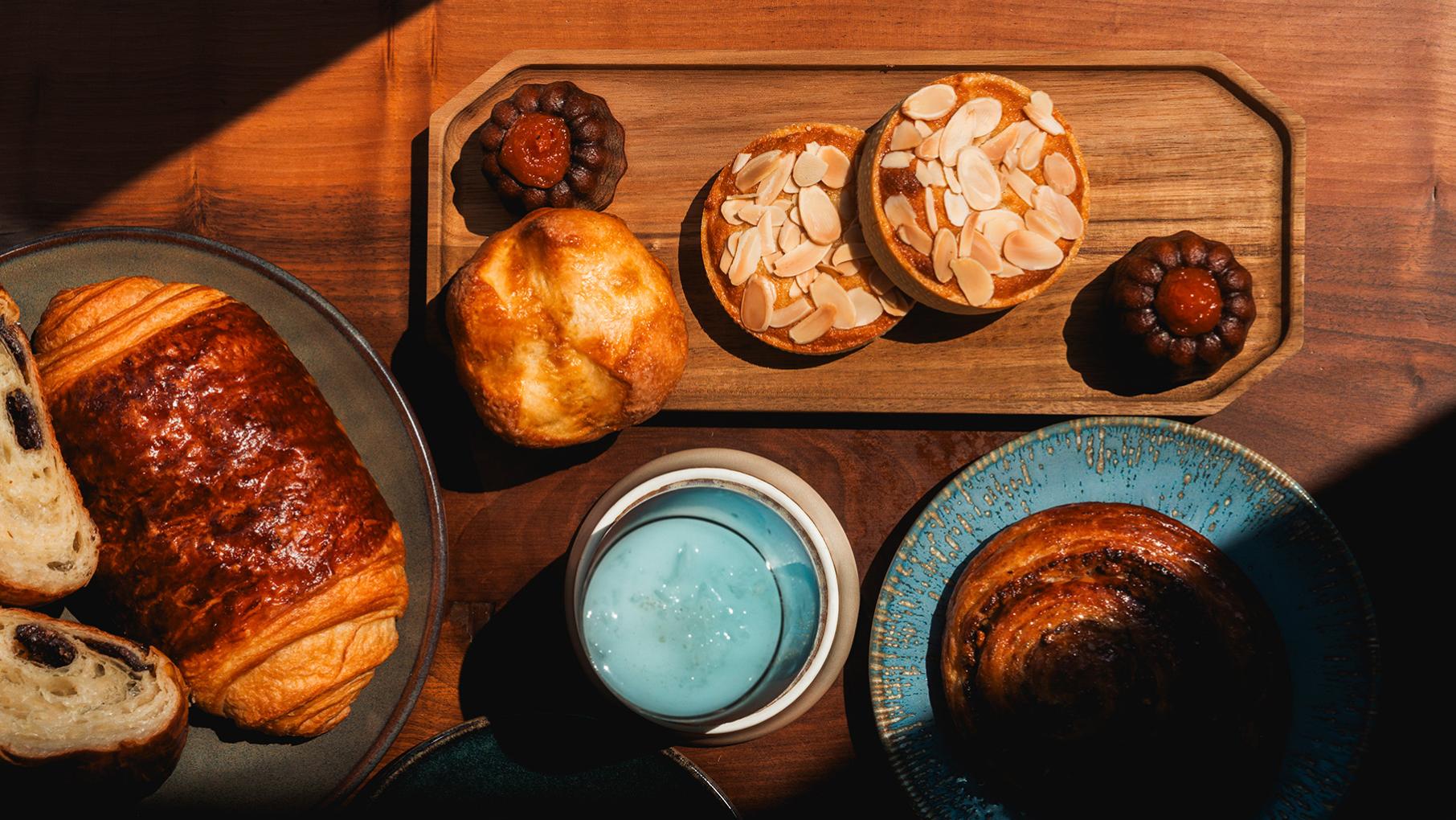 Pastries on various plates seen from above in a slant of sunlight on a table