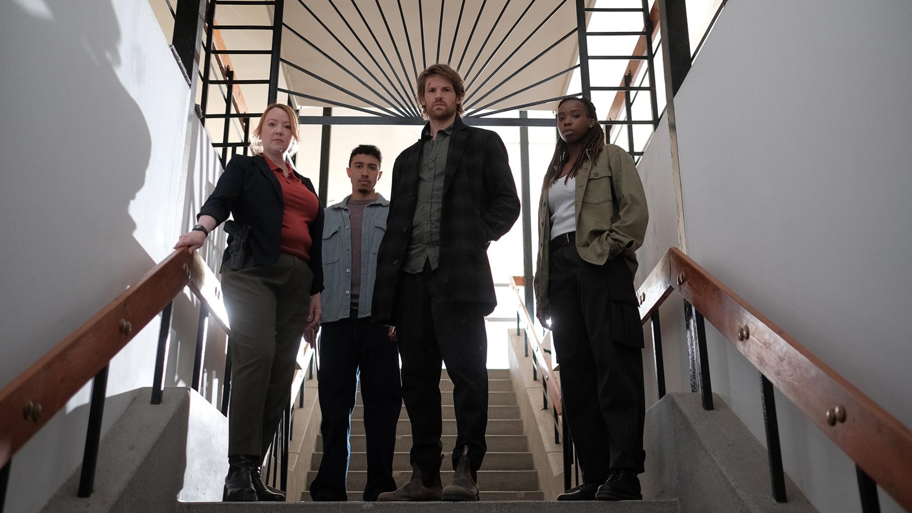 Lucas, Lapointe, Maigret, and Janvier stand at the top of a staircase