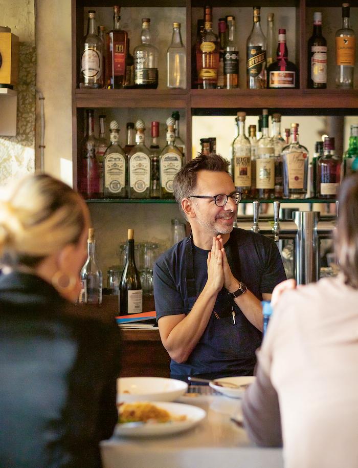 Jason Hammel stands behind the bar of his Lula Cafe and smiles with his hands clasped