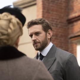 Alexander Blake looks at Miss Scarlet, who is facing away from the camera
