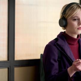 Patience Evans sits with headphones on at a bus stop holding a puzzle