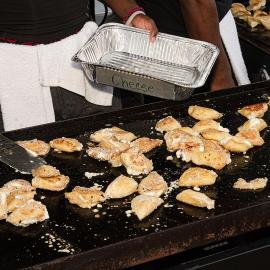 A worker turns pierogi on a griddle
