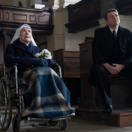 Sister Monica Joan in a wheelchair next to Bernie Mullucks in a pew in a church