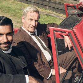 Alphy and Geordie sit in a red convertible with the top down