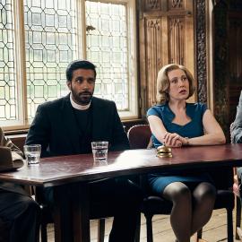 Geordie, Alphy, Miss Scott, and Leonard sit behind a table in an ornate hall