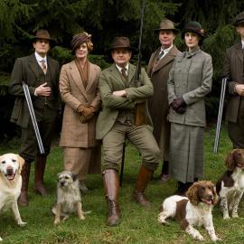 The Crawleys and other pose in hunting garb and guns outside with dogs