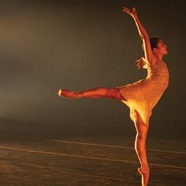A ballet dancer en pointe and another dancer standing behind them on stage