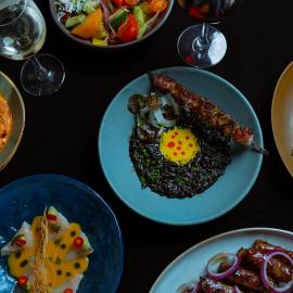 Plates of food and glasses of wine seen from above on a table