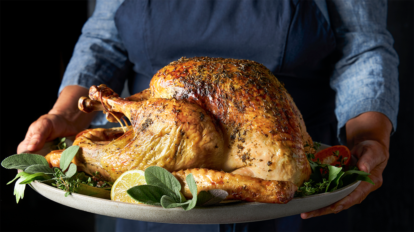 A person holding up a turkey on a platter