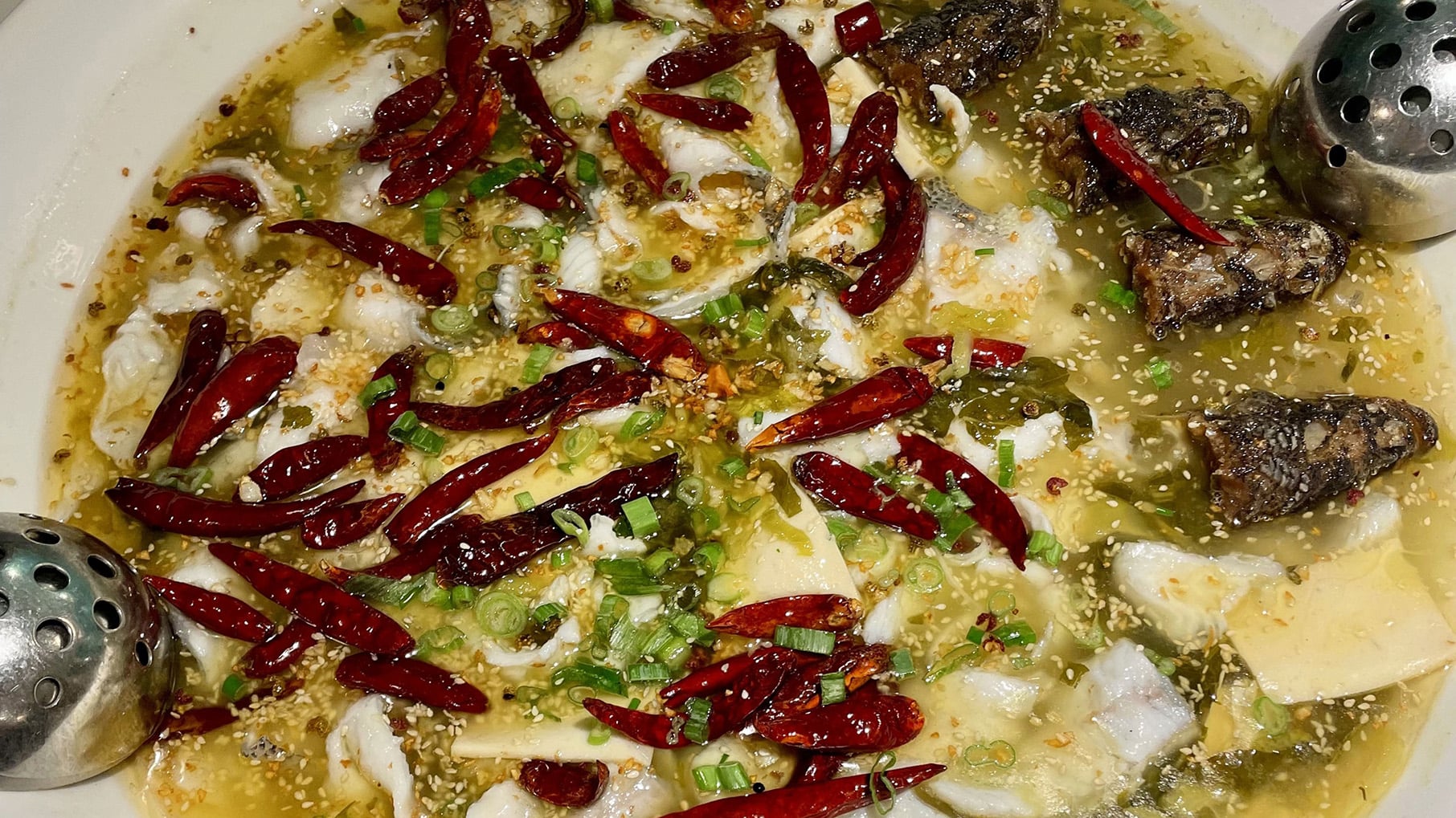A plate with fish and chiles in a green sauce